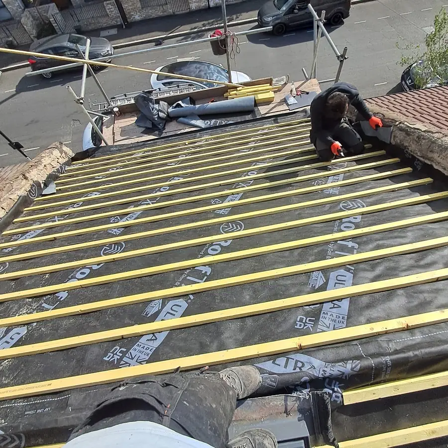 Roofer kneeling to fix battens on a re-roof
