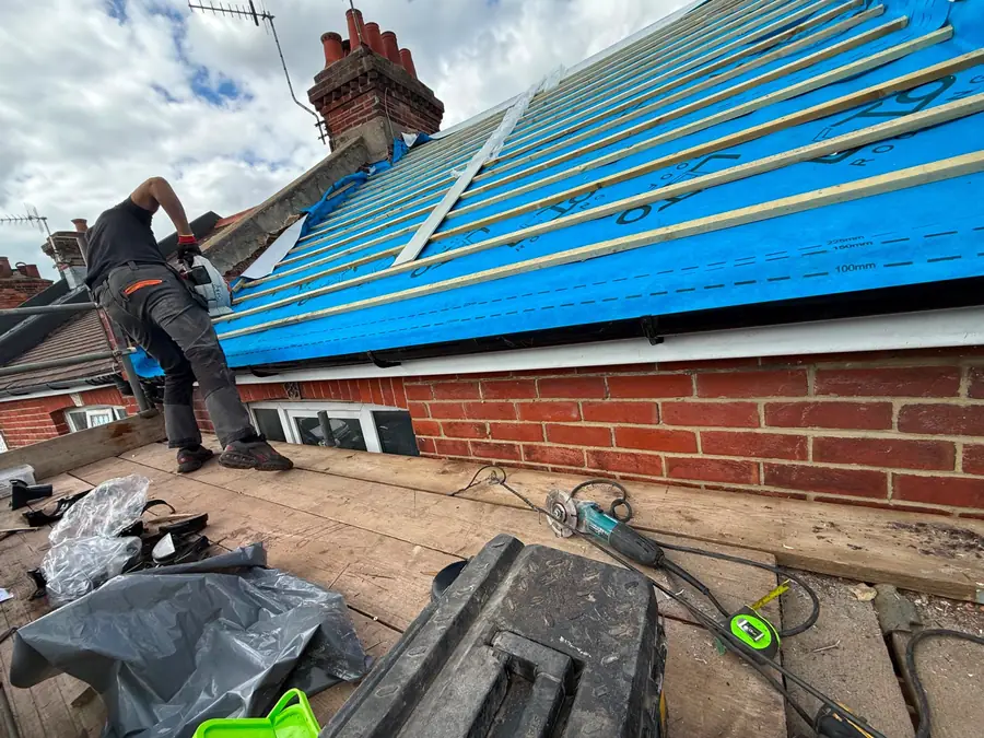 Crew fitting new blue breathable membrane on a re-roof