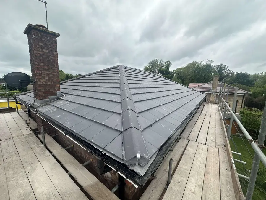 New grey tile hip roof finished, seen from the scaffold boards