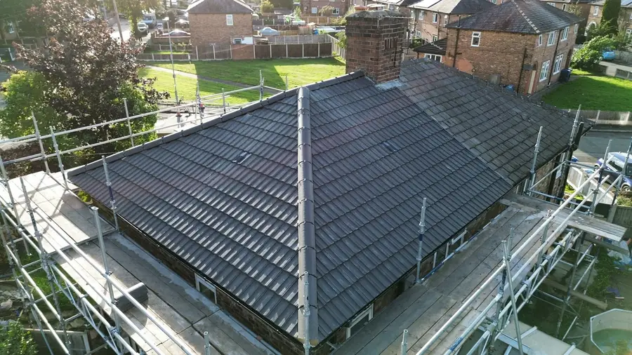 New grey tiled hip roof with dry hips, scaffold round the eaves