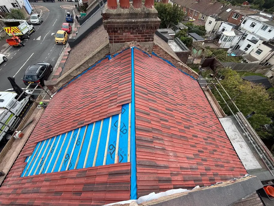 Red tile roof opened up with new blue membrane going in