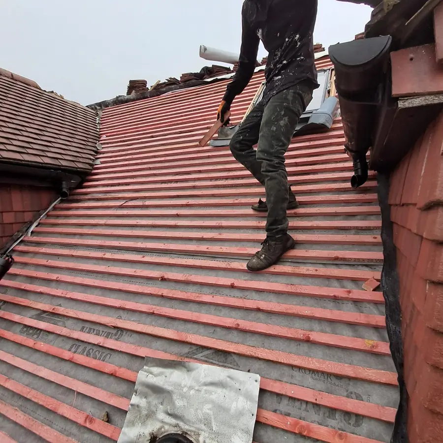 Roofer walking a red tile roof during the job