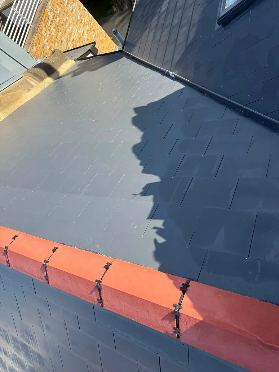 New slates down to the eaves beside an orange ridge