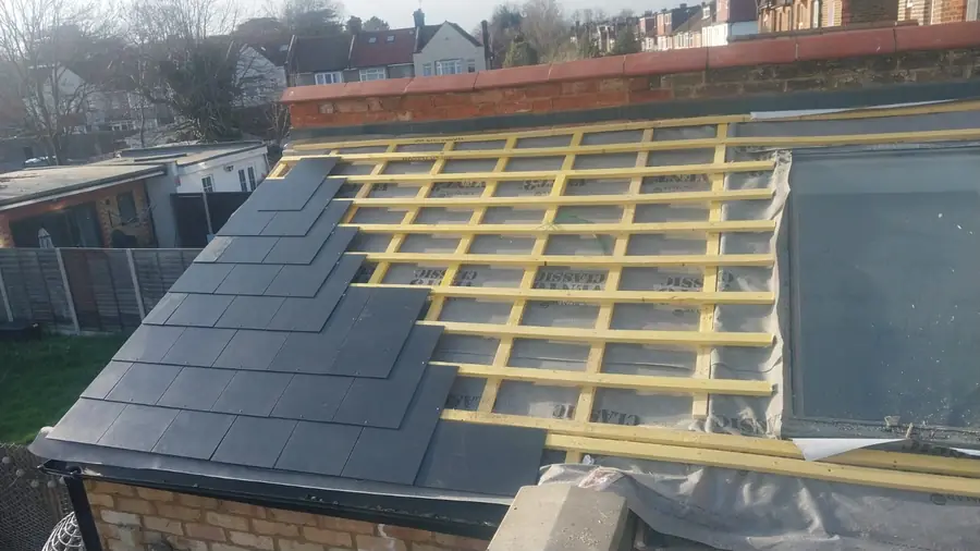 Slates being laid over battens on an extension roof